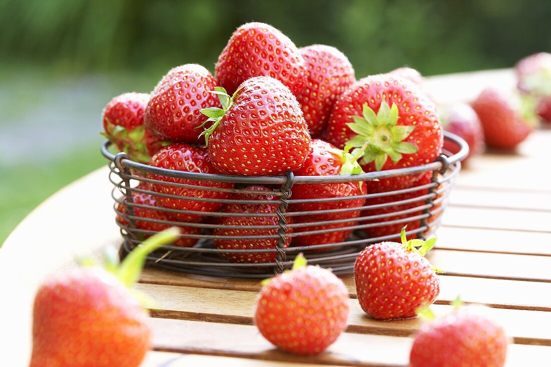 Frische Erdbeeren im Drahtkorb auf Holztisch
