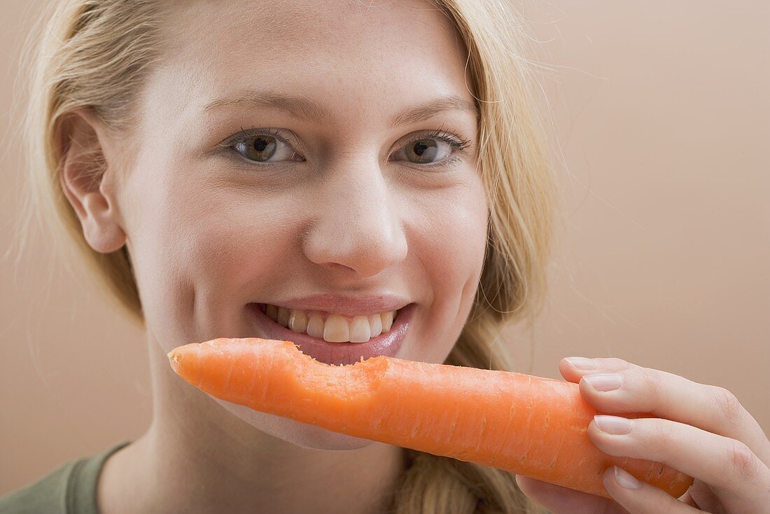 Woman holding a carrot with a bite taken