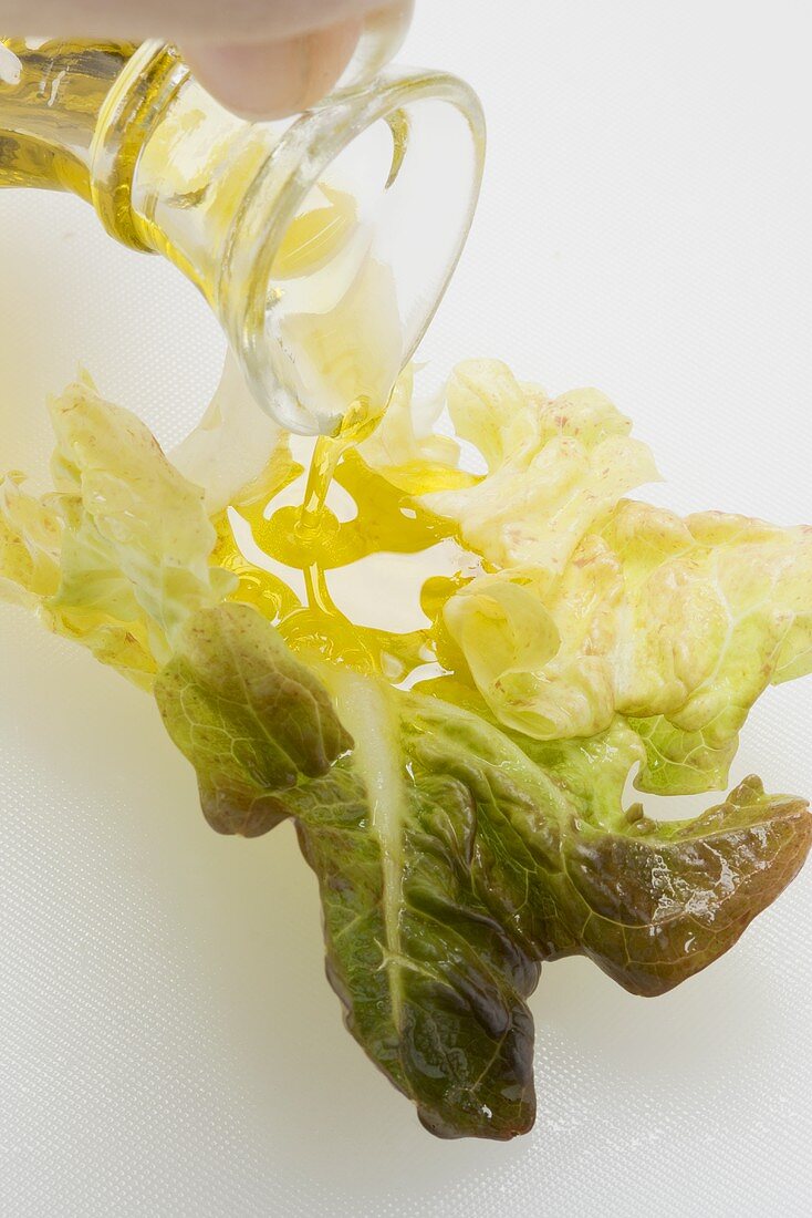 Pouring olive oil over oak leaf lettuce