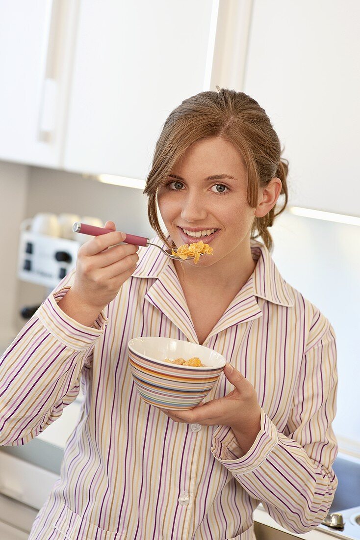 Young woman eating a bowl of cornflakes
