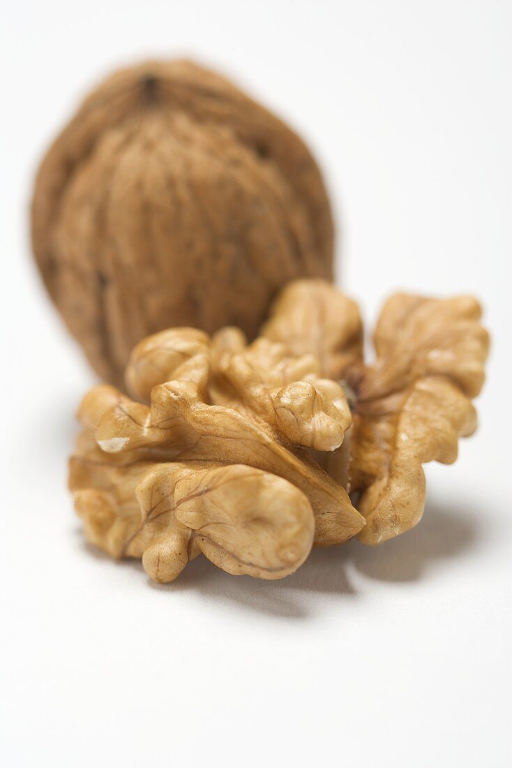 Shelled walnut in front of unshelled walnut