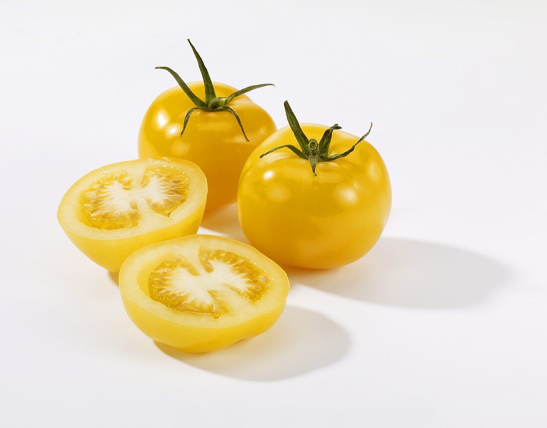Halbierte und ganze gelbe Tomaten