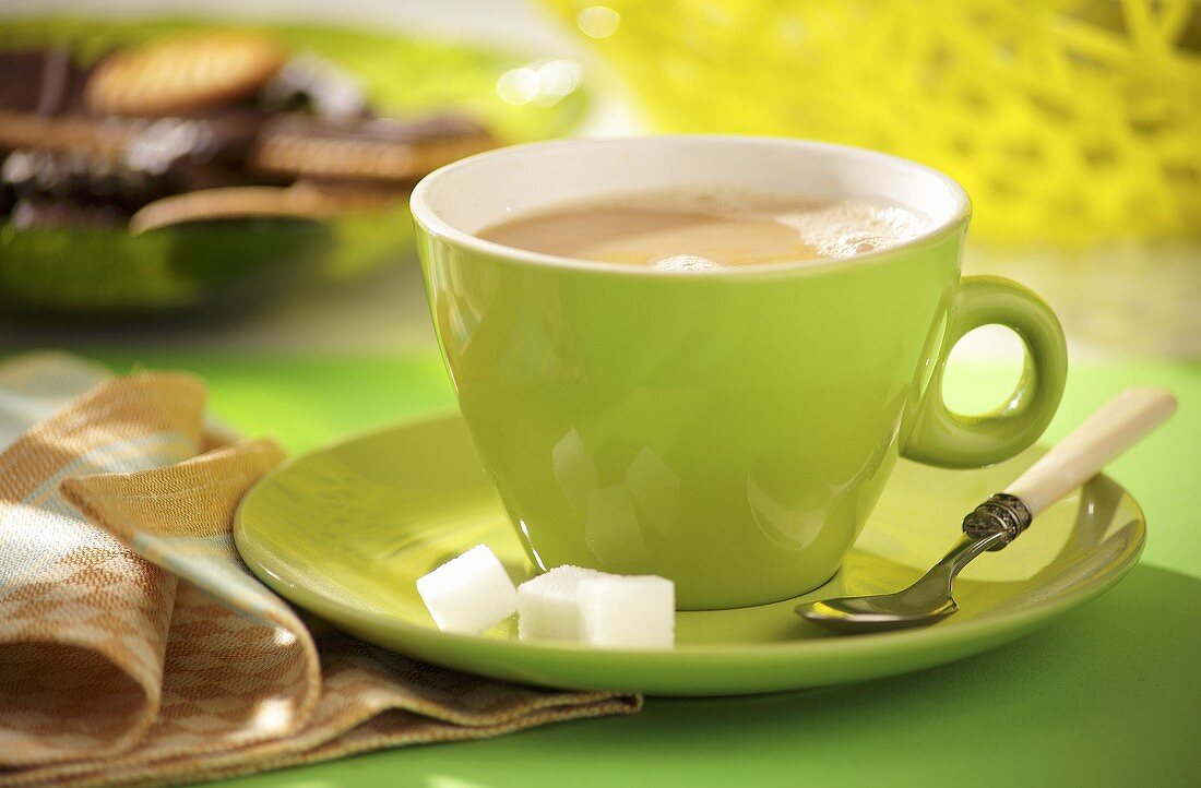 Milky coffee in green cup and saucer