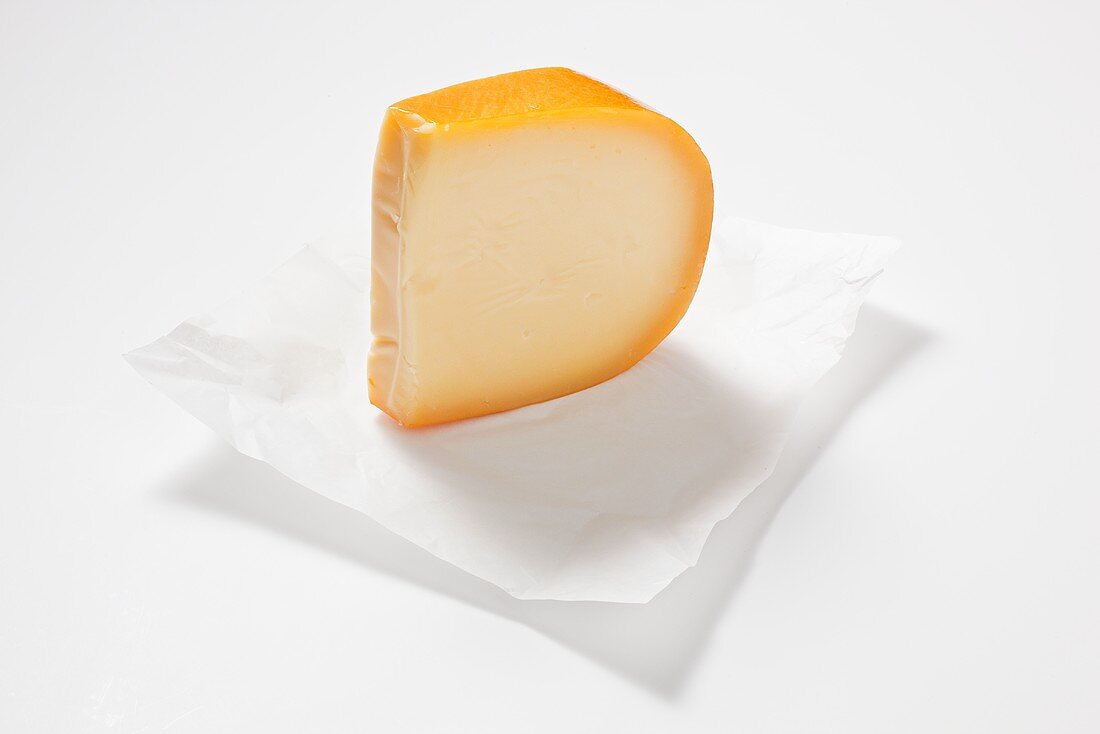 A piece of Gouda cheese on paper