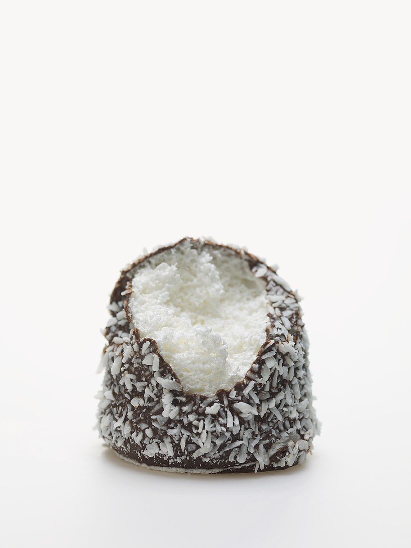 Chocolate teacake covered in grated coconut, a bite taken