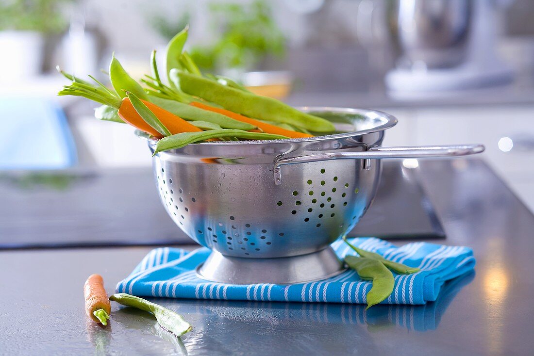 Fresh carrots and beans in a colander