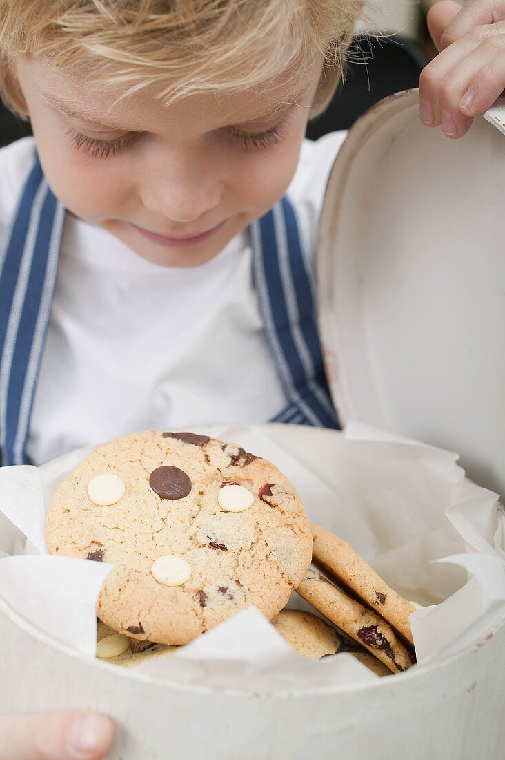 Junge betrachtet Chocolate Chip Cookie in Keksdose
