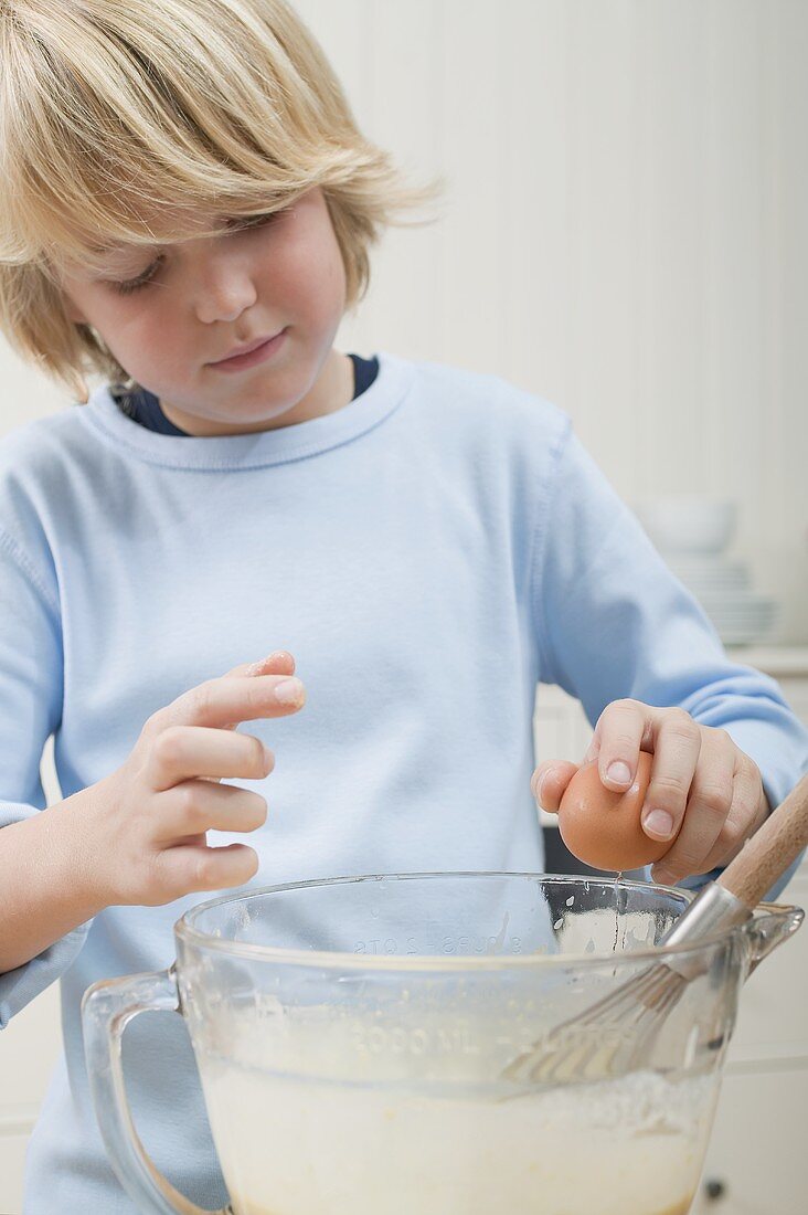 Boy making a sponge mixture (breaking an egg)