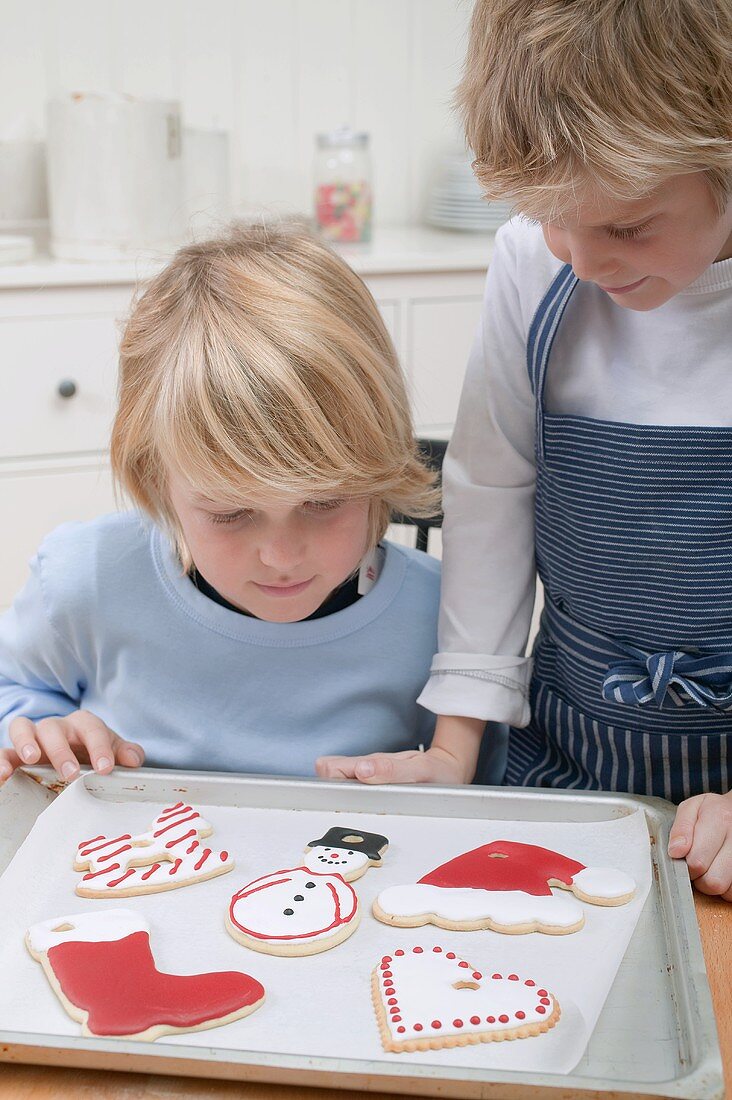 Zwei Jungen betrachten Weihnachtsplätzchen auf Backblech