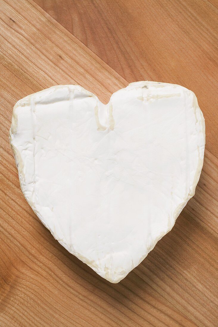 Heart-shaped Camembert on wooden background