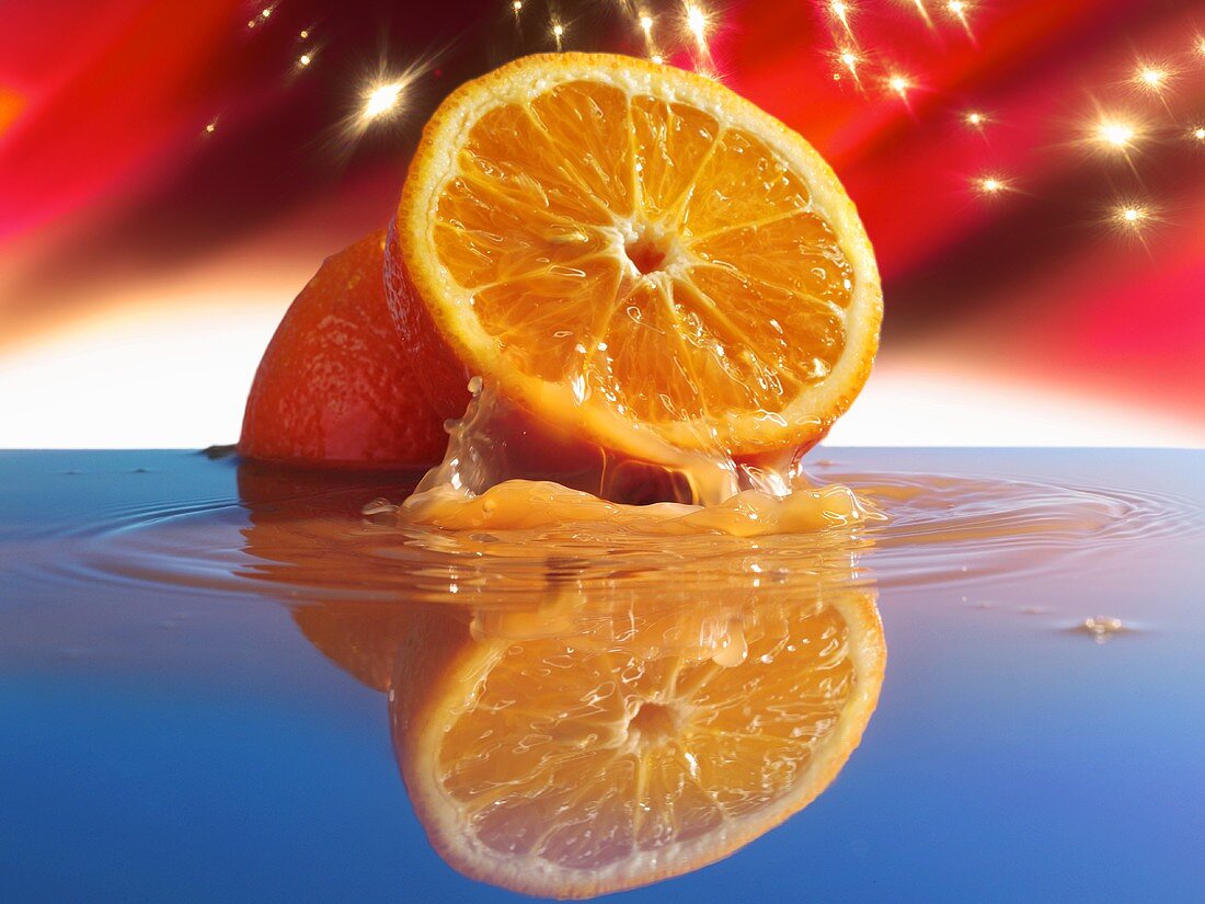 Zwei Orangenhälften im Wasser vor künstlichem Sternenhimmel