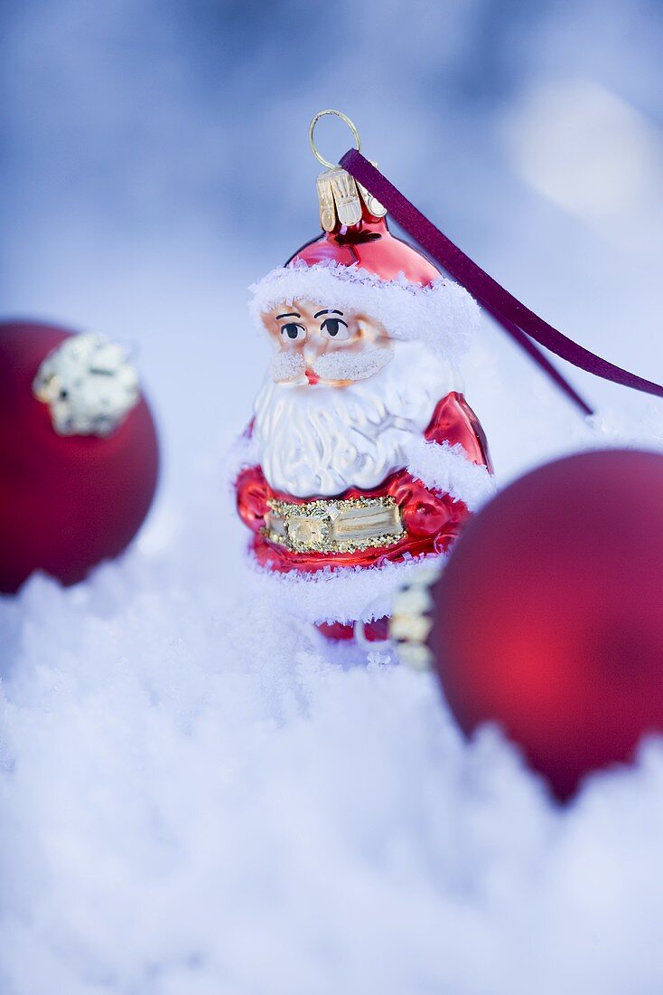 Weihnachtsmann und Christbaumkugeln im Schnee