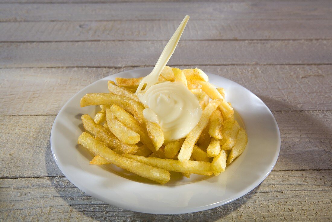Pommes frites mit Mayonnaise und Plastikgabel auf Teller