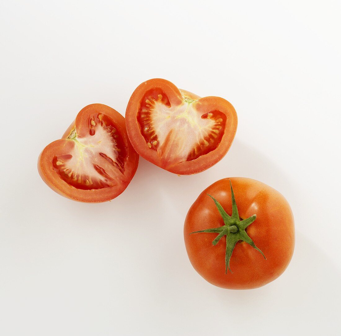 Ganze Tomate und zwei Tomatenhälften