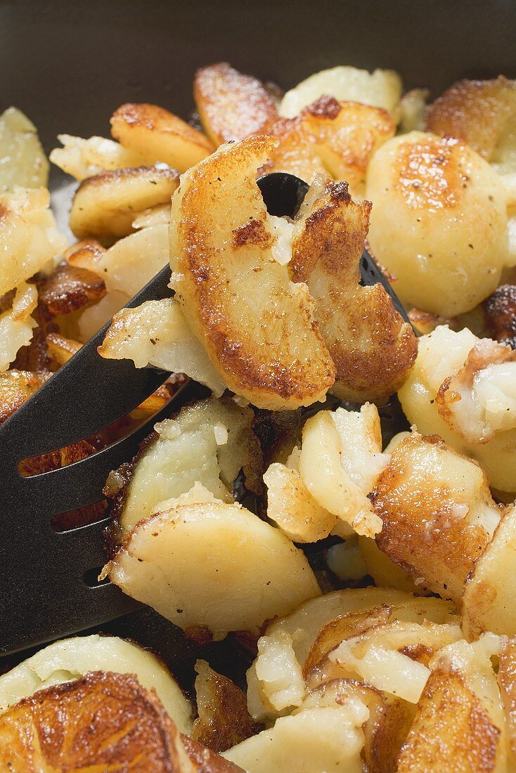 Fried potatoes in frying pan (close-up)