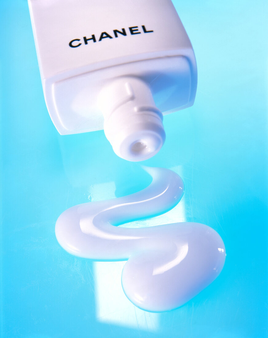 Close-up of white cleanser by Chanel and tube squeezed out on blue background