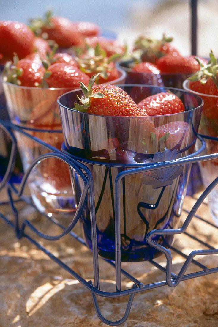 Blaue Glasbecher mit Erdbeeren gefüllt