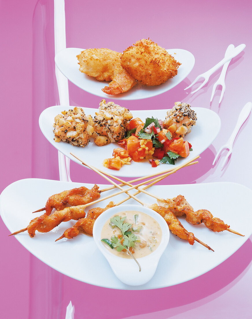 Several dishes on white plates against pink background