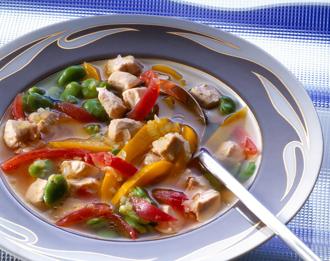 Close-up of chicken soup with tomatoes and peppers in bowl