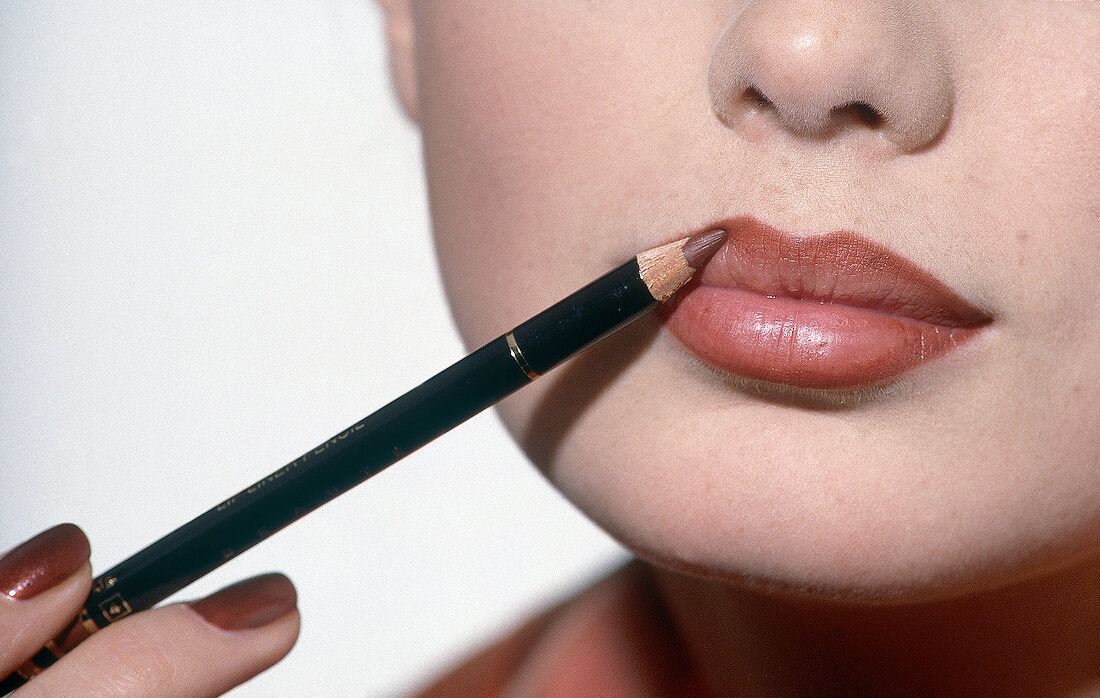 Close-up of woman applying lip liner with pencil