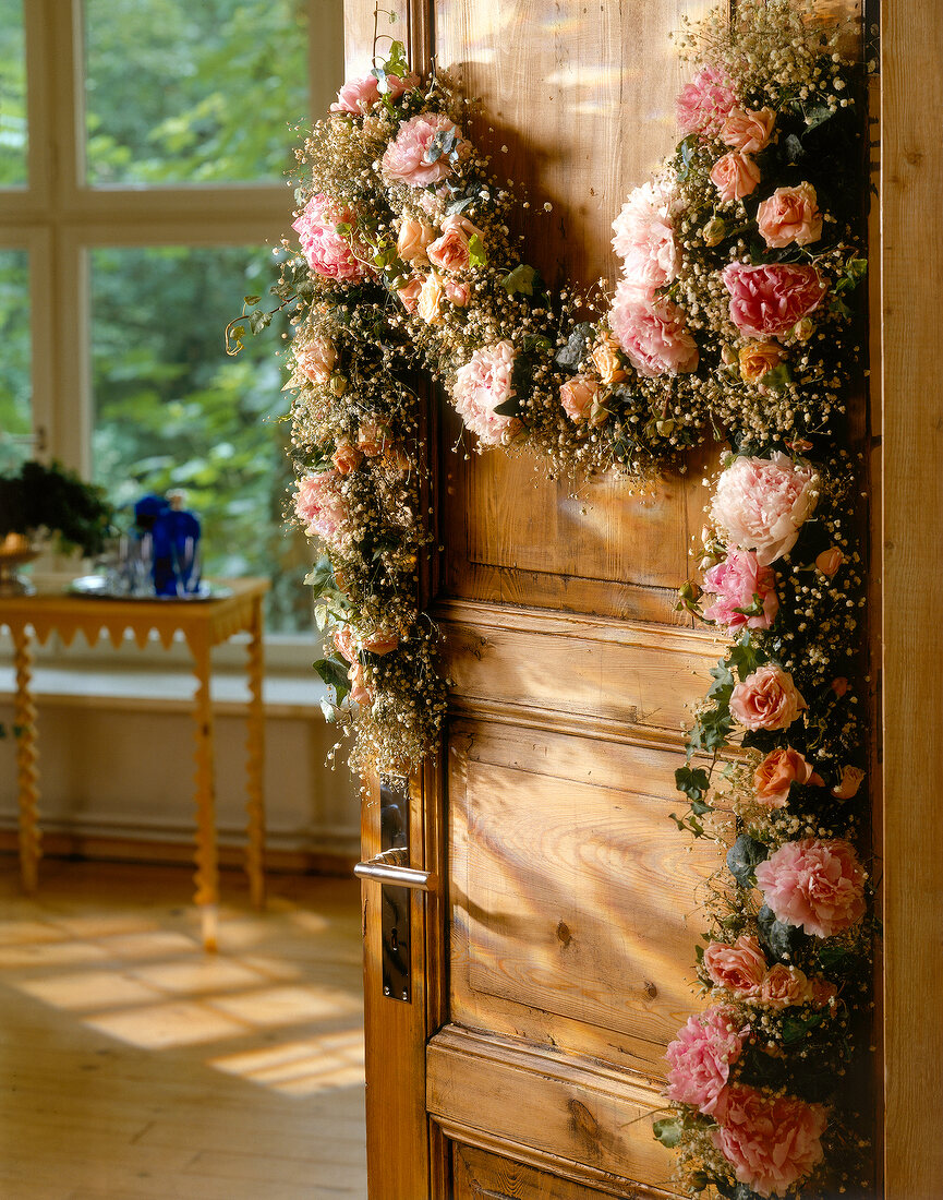 Close-up of garland made of roses, ivy and gypsophila on door