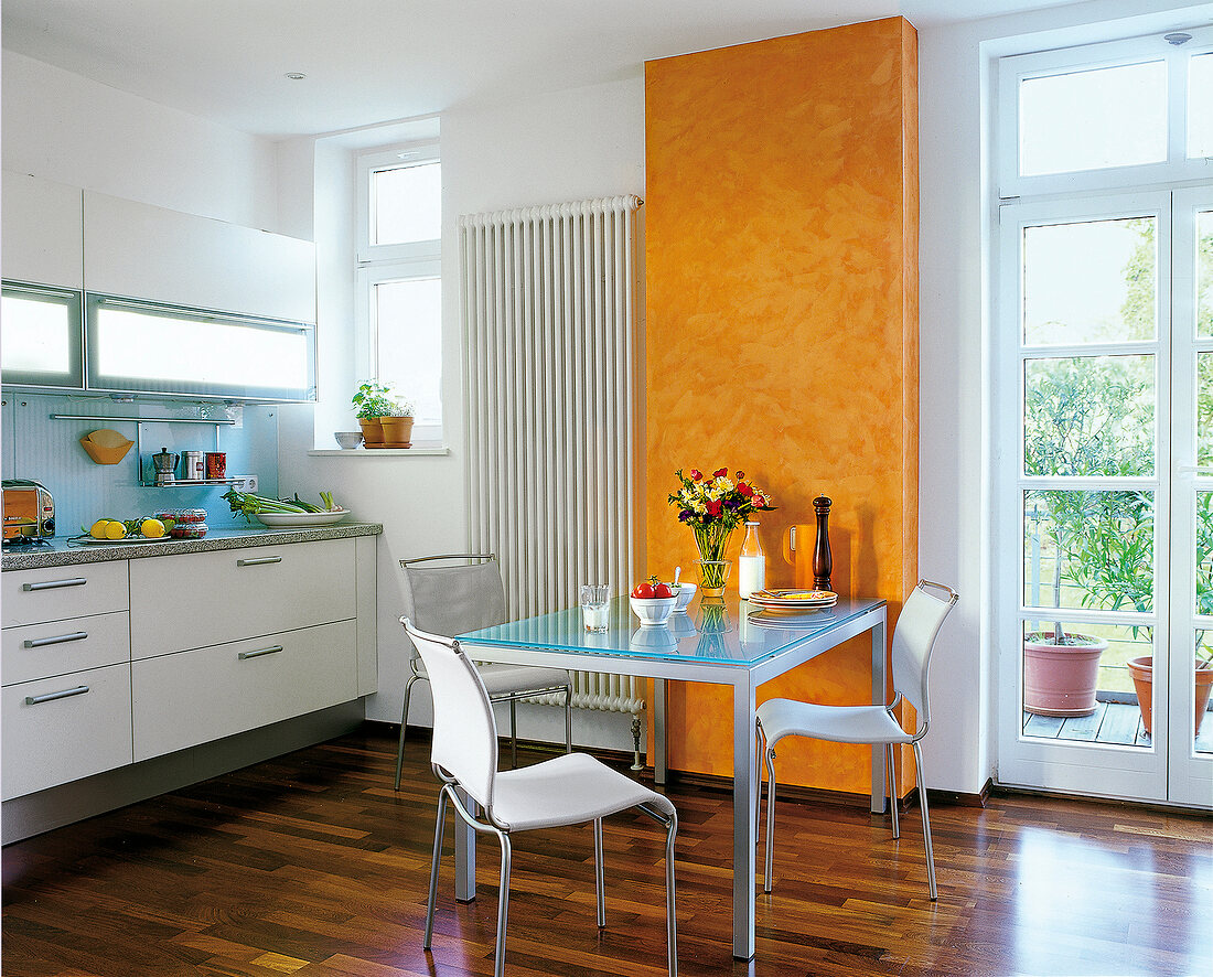 Küche in Weiß: Metalltisch mit GlasPlatte, Stühle, Teil der Wand gelb
