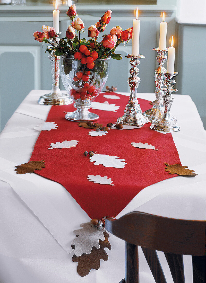 Esstisch mit rotem Filzläufer, Blumenvase und Kerzenständer