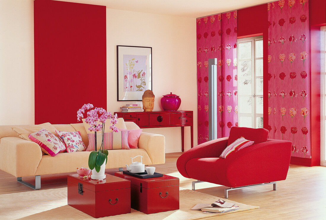 Red and pink living room with armchair, sofa and Buddha head statue on table