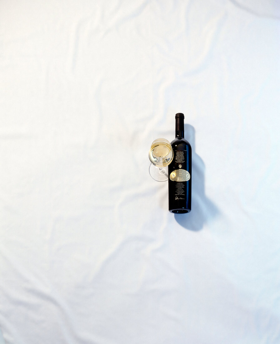 Bottle of white wine with wine on white background