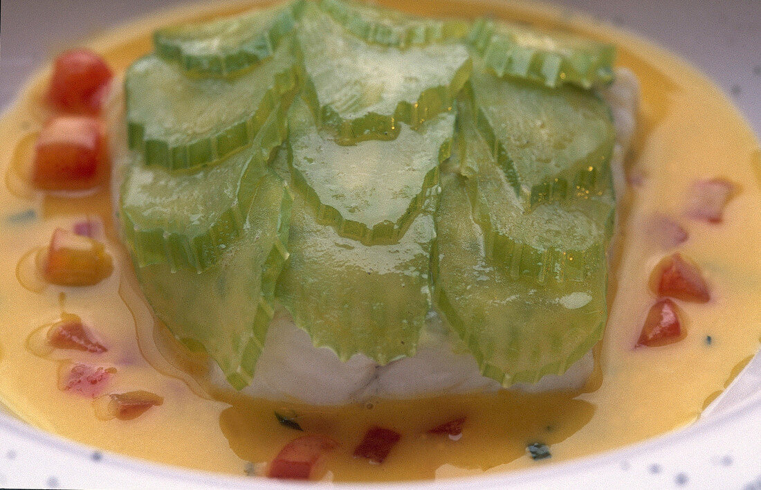 Close-up of turbot with perennials celery flakes on tomato and tarragon fumet