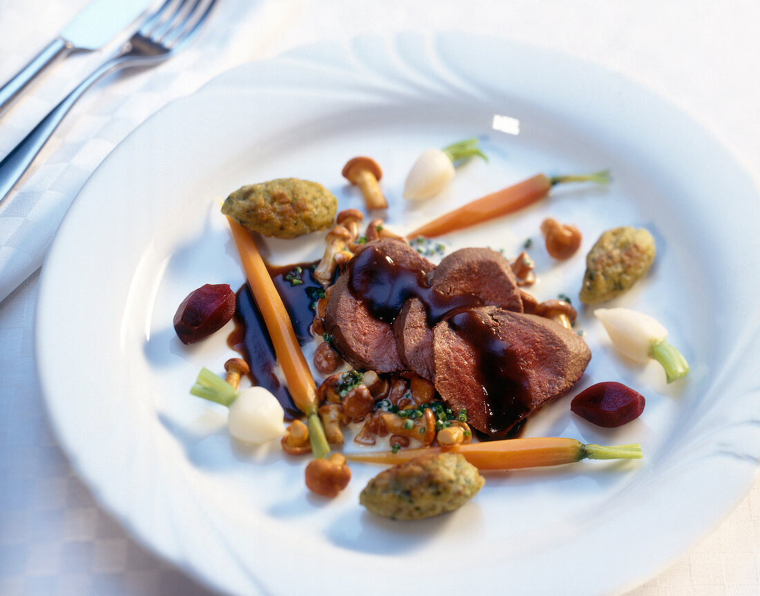 Close-up of poached vension fillet in chanterelles and swabian brotknopfle on plate