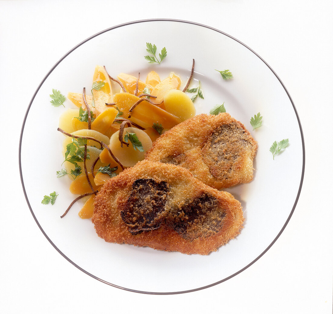 Veal schnitzel with warm potato and truffle salad on plate