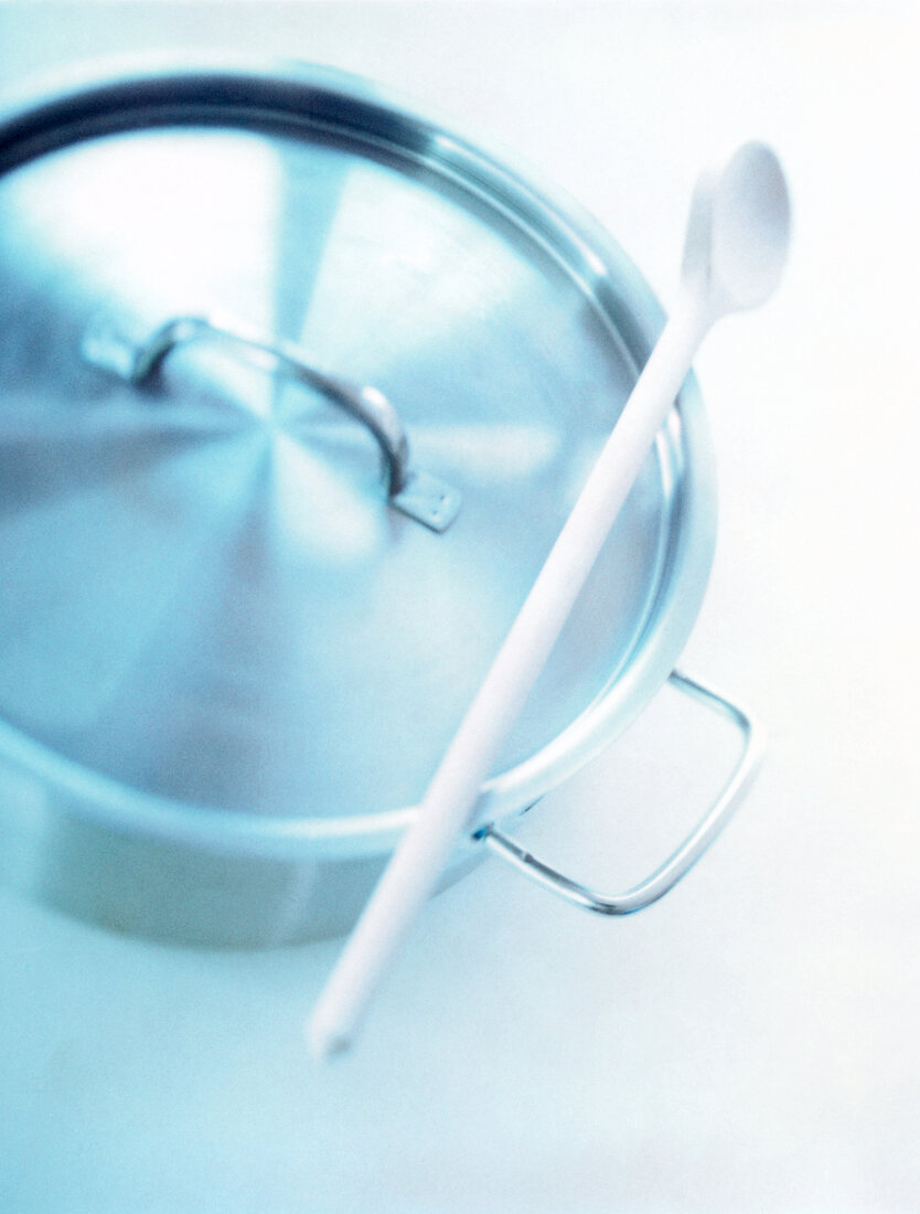 Close-up of stainless steel pot with spatula on white background