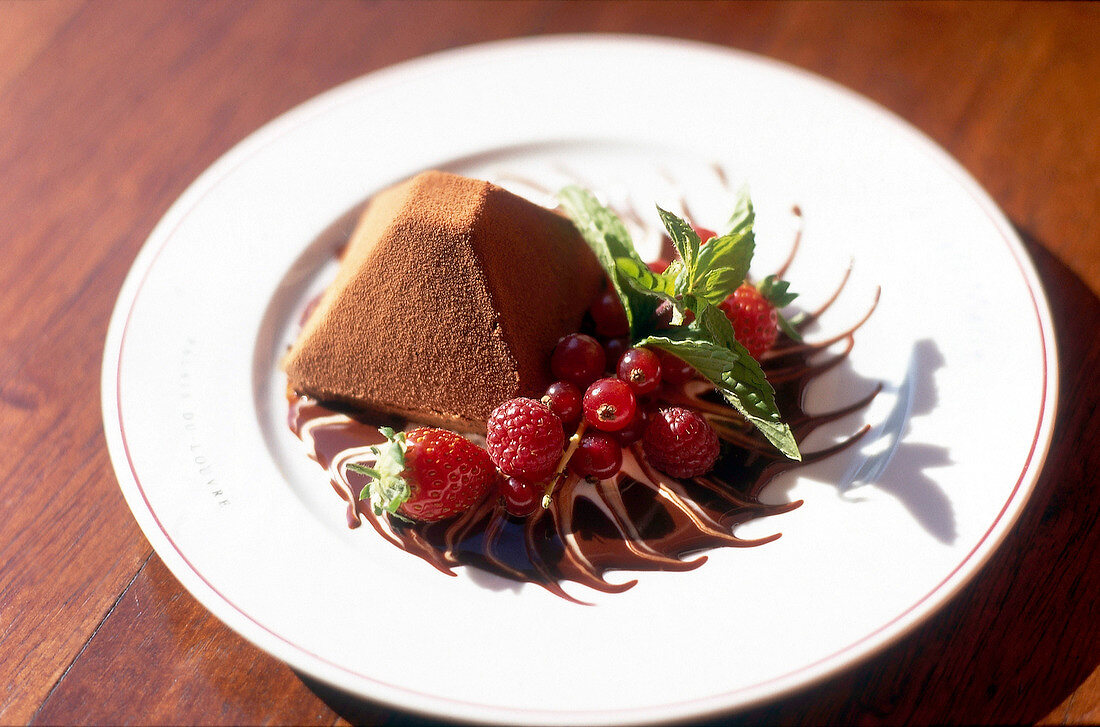 Chocolate pyramid with fresh berries and mint leaves on plate