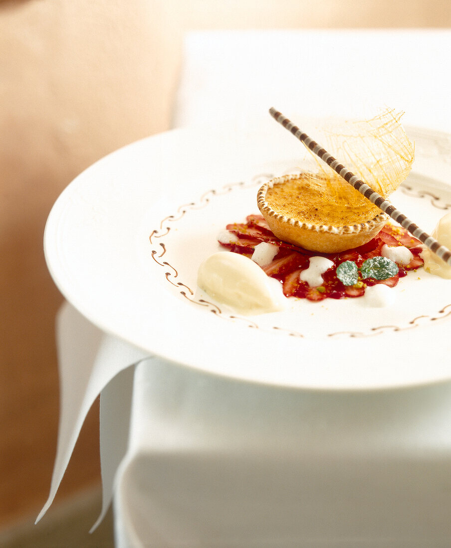 Caramelised sour cream tart with strawberries and champagne ice on plate