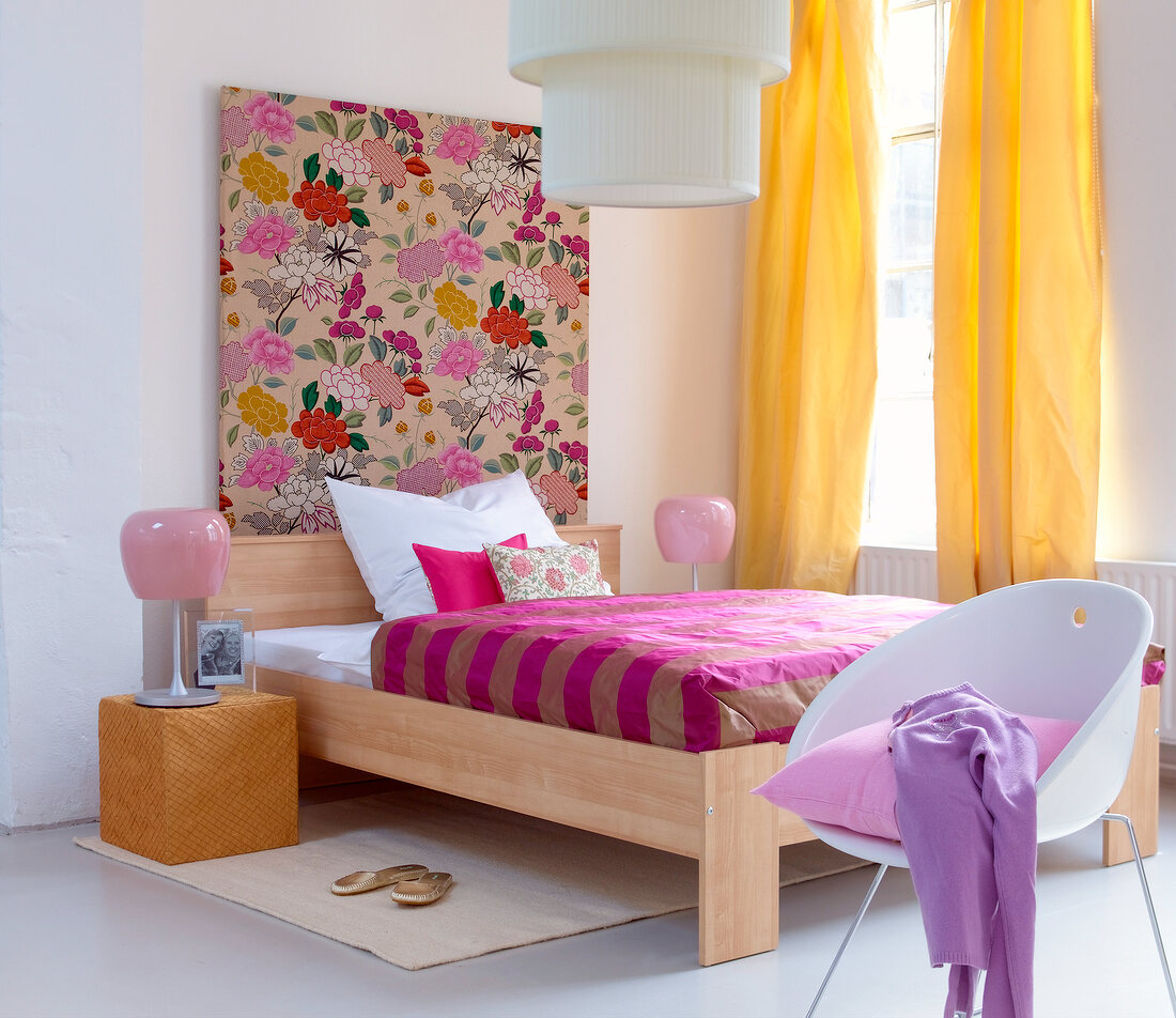 Colourful bedroom with chair, curtains and floral patterned fabric covered frame