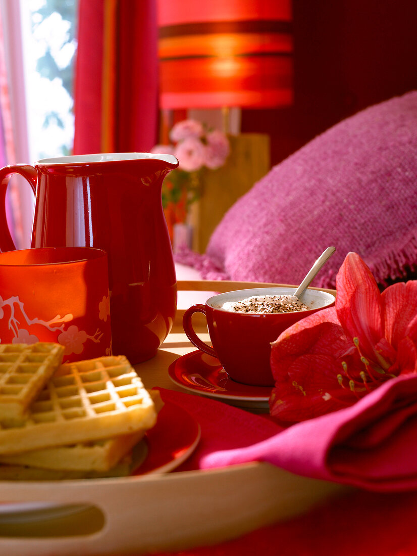 Tablett mit Cappuccino, Waffeln und Blüte