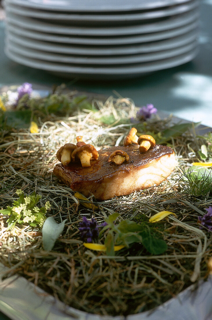 Close-up of cooked sturgeon and mushrooms served on haystack