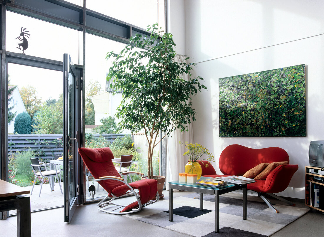 Living room with red armchair and wall painting with leaves