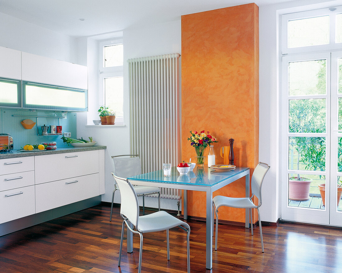 Küche in Weiß: Metalltisch mit Glas- Platte, Stühle, Teil der Wand gelb