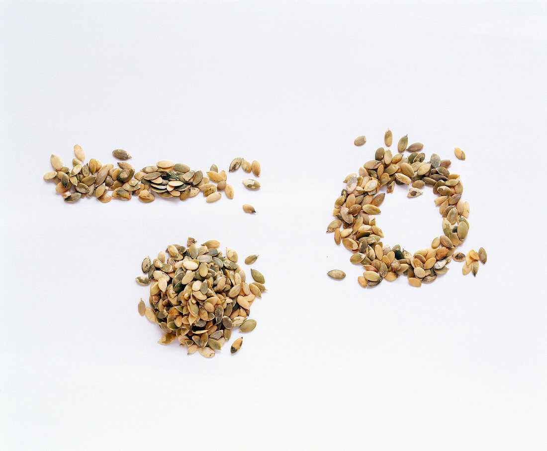 Different shapes made from pumpkin seeds on white background