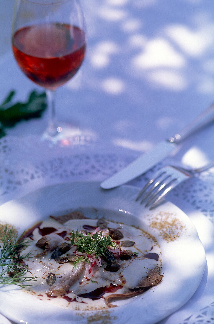 Boiled beef carpaccio with potato dressing served with a glass of wine