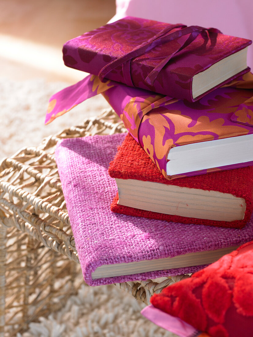 Close-up of colourful stack of books on wicker chair