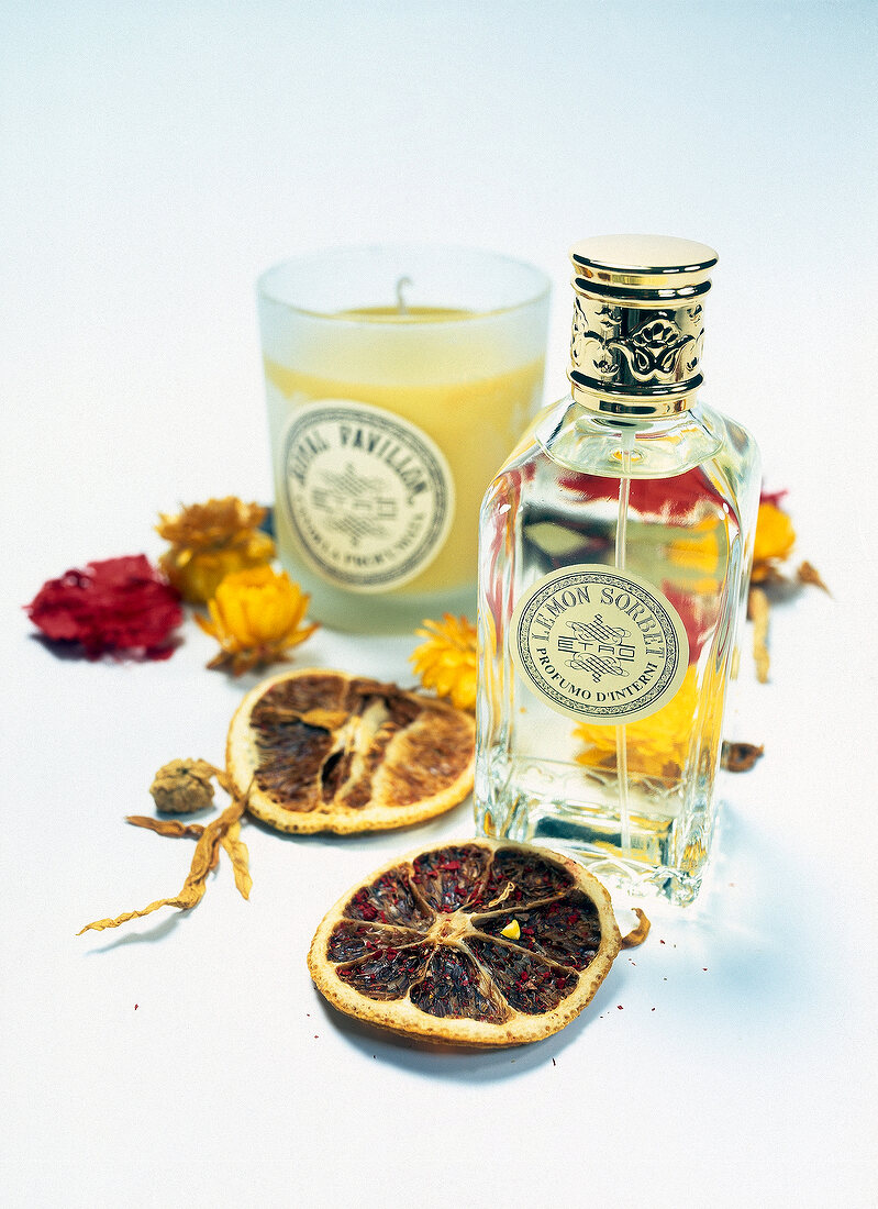 Cocktail with dried orange slices, flowers and scented candle on white background