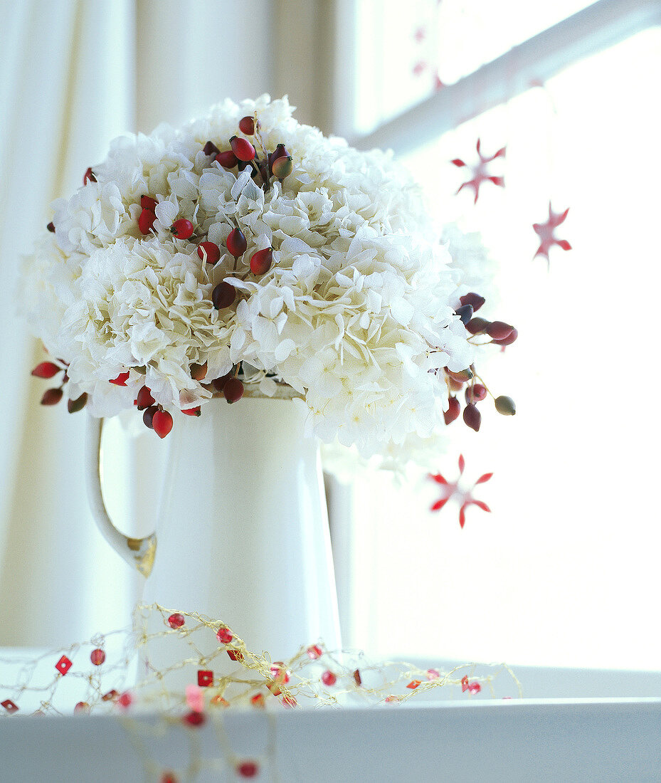 Blumenstrauß aus weißen Hortensien + Hagebutten in weißem Krug