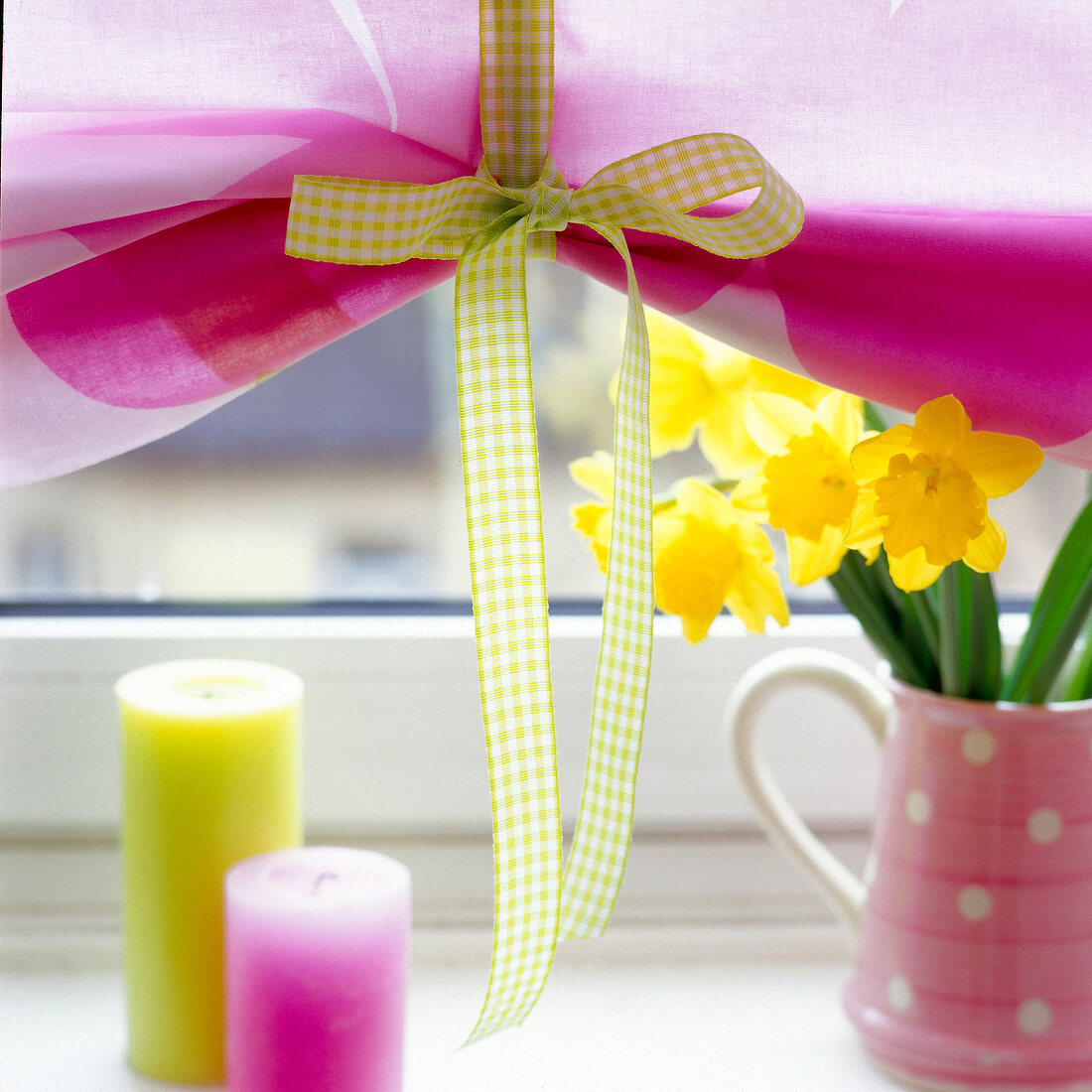 Close-up of green fabric loops for holding roller blind with candles in front