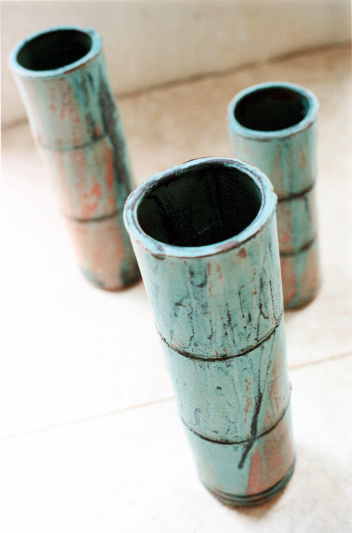 Close-up of three green bamboo shaped flower vases on floor