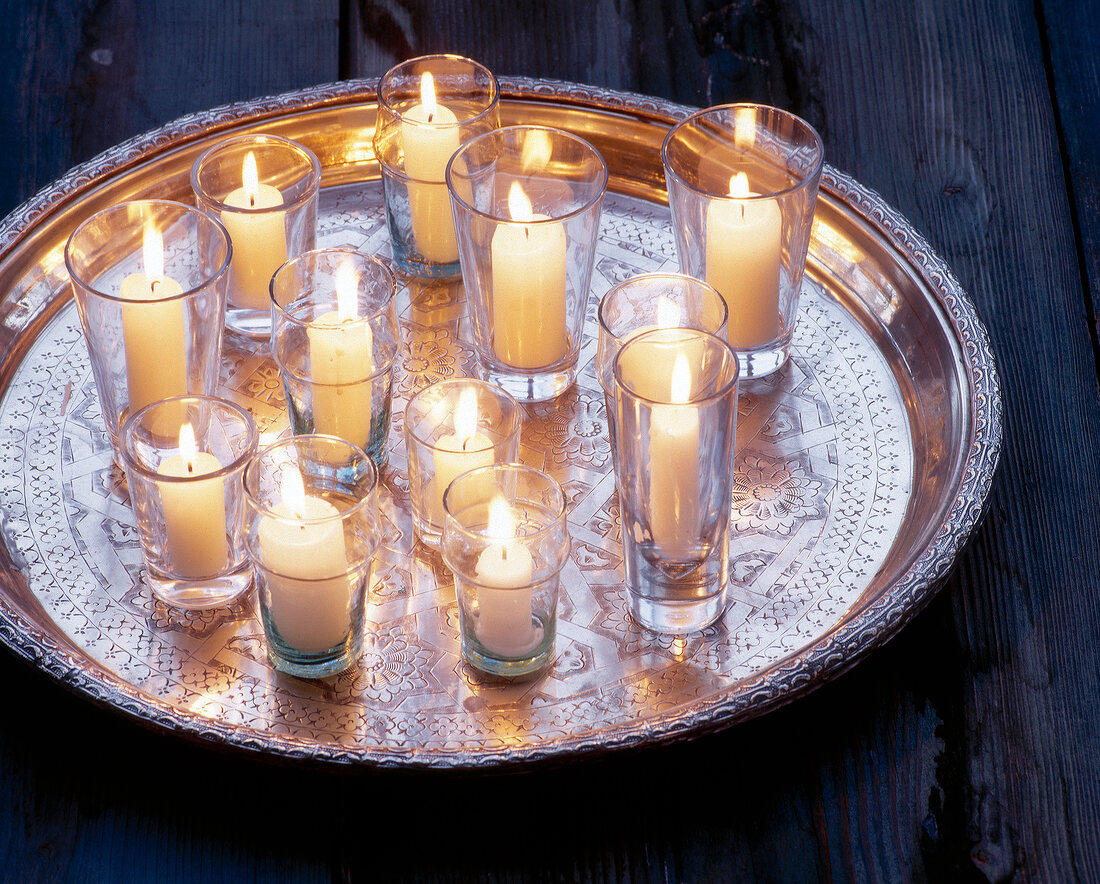 Lit candles in glasses on silver tray