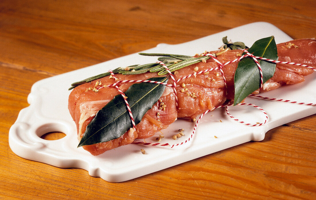 Close-up of fillet wrapped with spices and herbs on chopping board