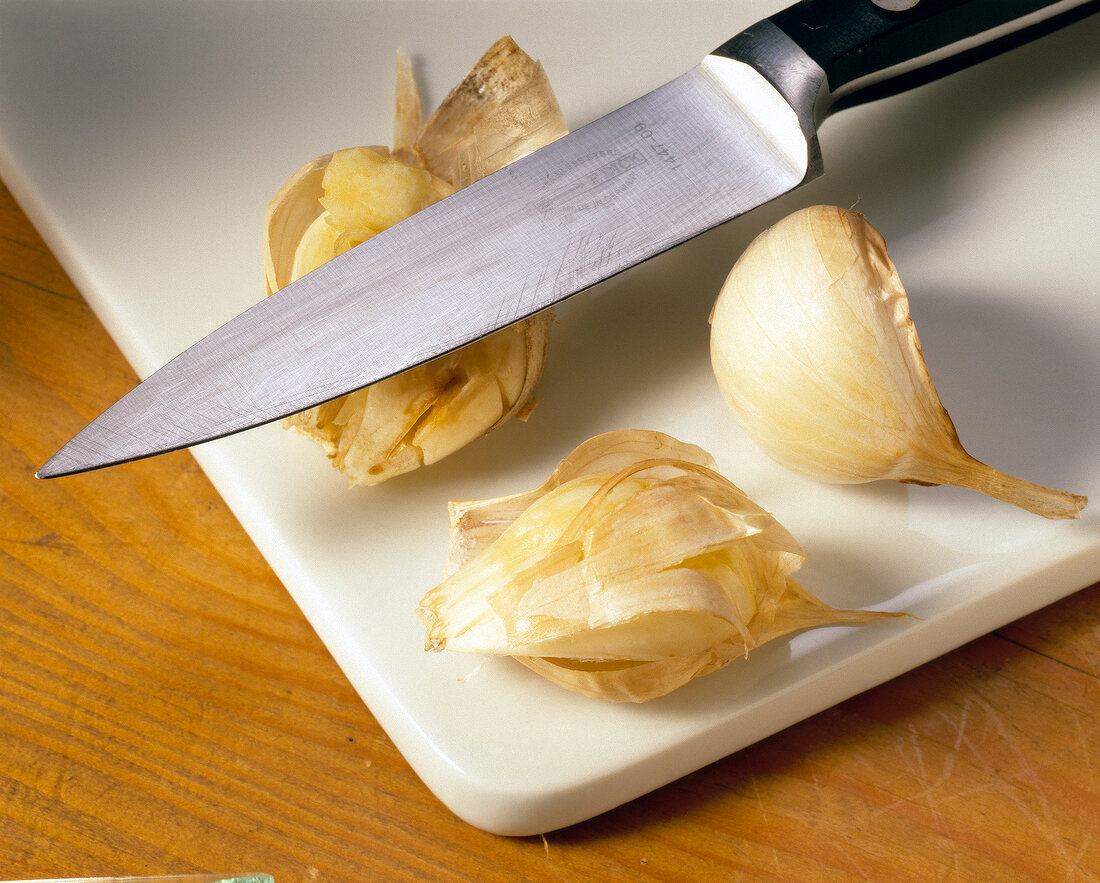 Cloves of garlic with a knife on cutting board